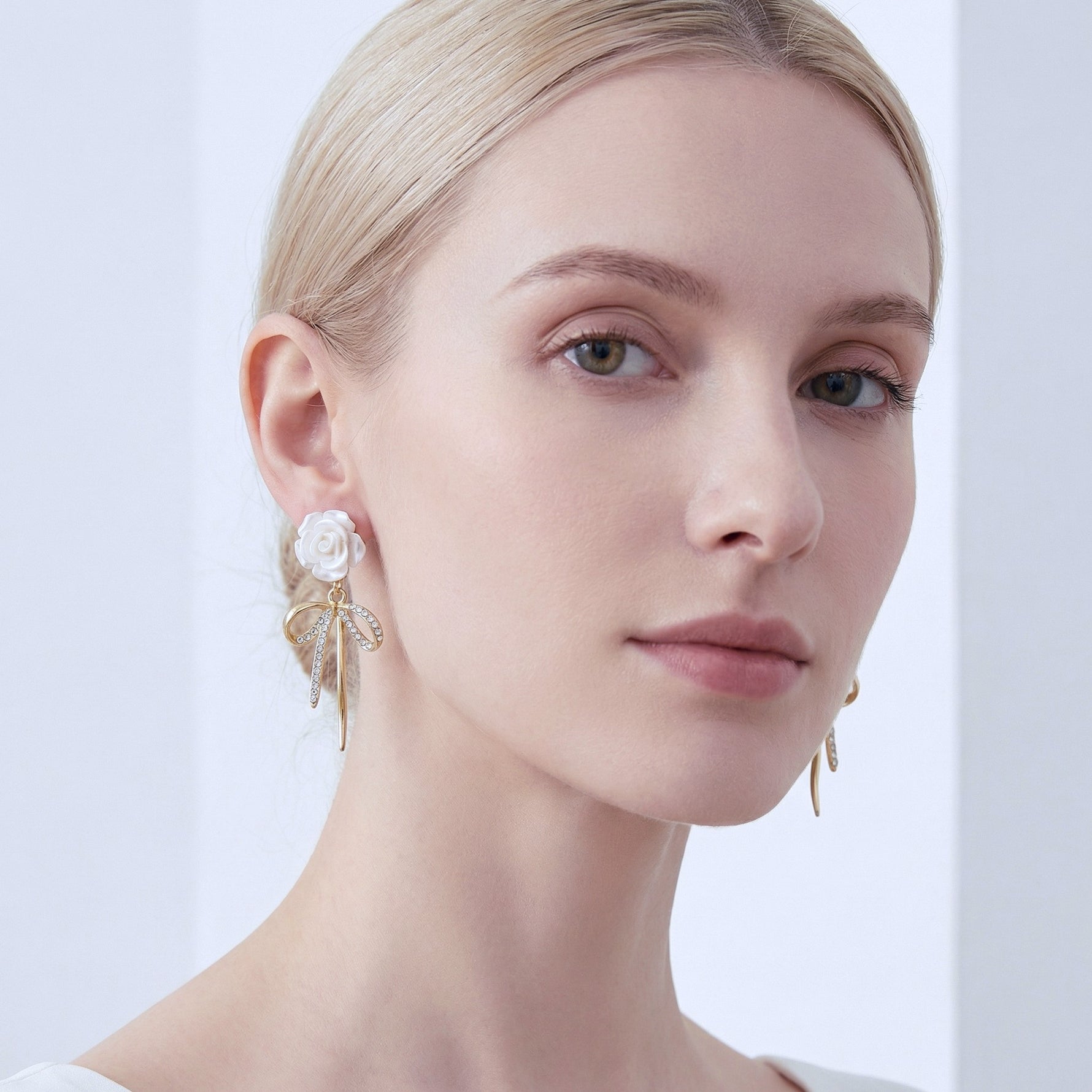 Close-up of a woman wearing White Rose Bow Drop Earrings